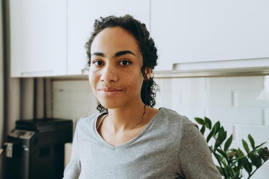 Young black woman smiling and looking at camera in kitchen photo