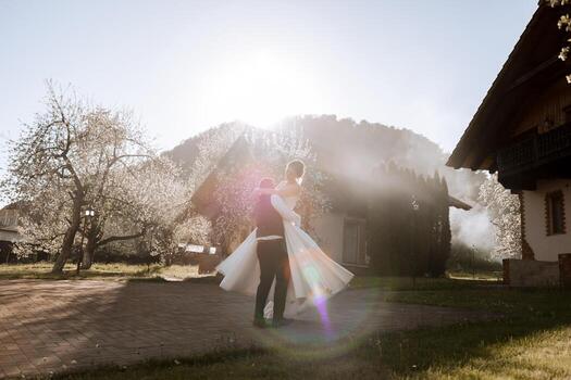 The bride in the arms of the groom. The groom is holding his bride in his arms and circling against the background of a beautiful park. photo