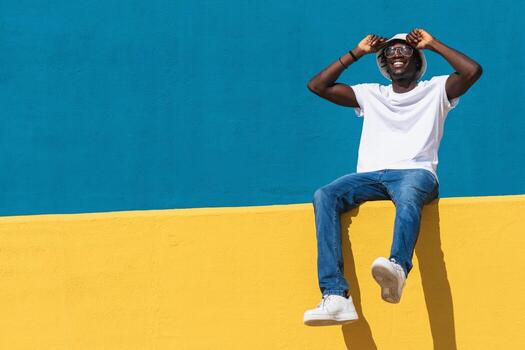 A man sitting on a wall with his hands on his head. photo